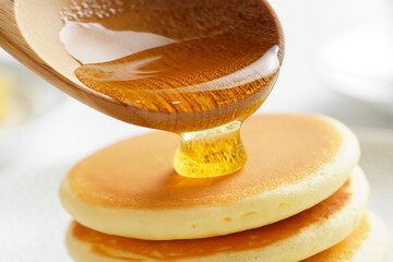 Golden syrup poured onto fluffy pancakes honey pouring