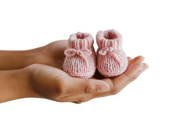 two hands holding baby booties. The focus is on one pair, and they hold it out to show off the beautiful pastel pink knitted baby shoes 