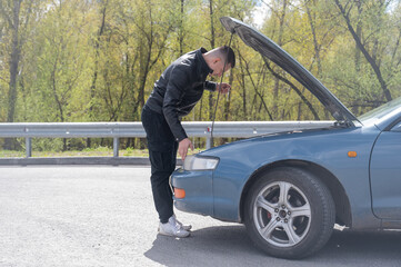 Caucasian man checking engine oil level in his car. 