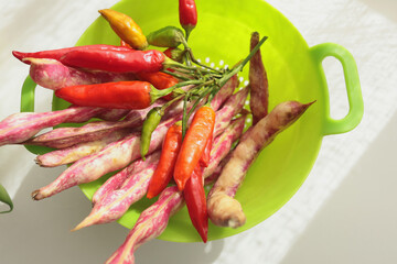 Bunch of red peppers and pink beans in green colander. Seasonal food and farm organic produce. 