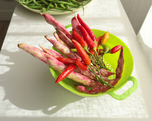 Bunch of red peppers and pink beans in green colander. Seasonal food and farm organic produce. 