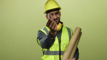 Hispanic man wearing a safety vest and hardhat makes a heart gesture with fingers against a yellow...