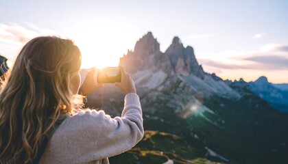 Woman taking photo of mountains at sunset.