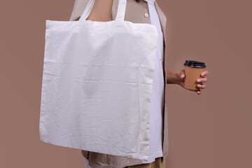 Carrying textile shopper, eco tote bag, drinking from takeaway coffee cup