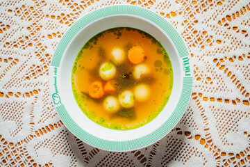 Delicious vegetable soup features colorful dumplings and fresh herbs in a charming setting