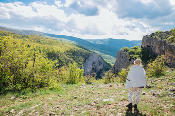 tourist looking at beautiful landscape on mountains, green forest and blue sky with clouds
