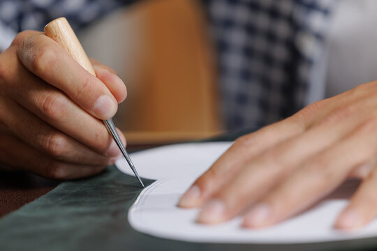 Male tailor cutting leather with precision craftsmanship