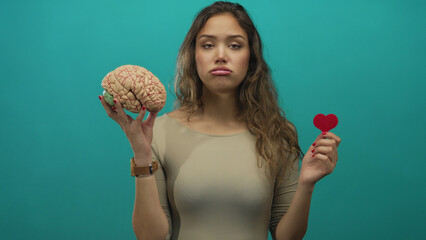 Woman with brain and heart on isolated green background, depicting choice between intellect and...