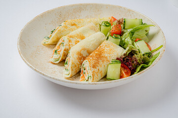 Delicious rolled pancakes filled with herbs, paired with a vibrant salad of tomatoes and cucumbers