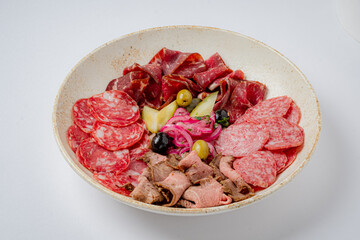 Delicious assortment of cured meats arranged artfully with pickled vegetables and olives