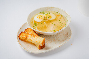 Warm broth filled with tender ingredients, topped with sliced eggs and served with toasted bread