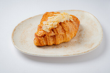 A delicious almond croissant on a textured plate, perfect for a treat