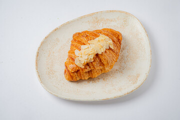 Golden croissant topped with almond slices awaits your morning enjoyment on a rustic plate