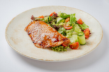 Grilled salmon fillet drizzled with sesame sauce, served alongside a vibrant garden salad