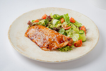 A succulent salmon fillet glazed with a savory sauce, accompanied by a refreshing salad