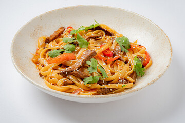 A satisfying bowl of beef noodles topped with vibrant peppers and fresh herbs awaits enjoyment