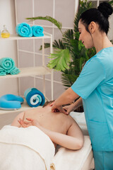 Massage therapist doing medical back and body massage to woman