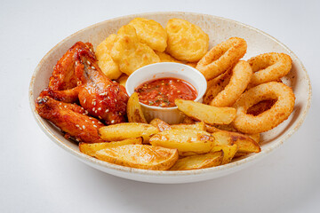 A tempting assortment of crispy wings, savory onion rings, and golden fries served with zesty sauce