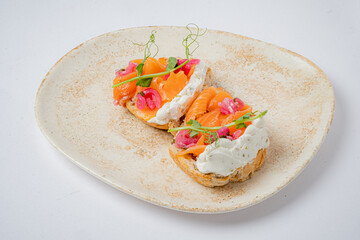 An open-faced sandwich with smoked salmon, creamy cheese, and pickled onions delights the palate