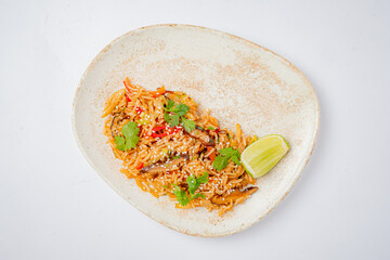 Stir-fried rice showcases colorful vegetables, garnished with fresh coriander and lime for zest