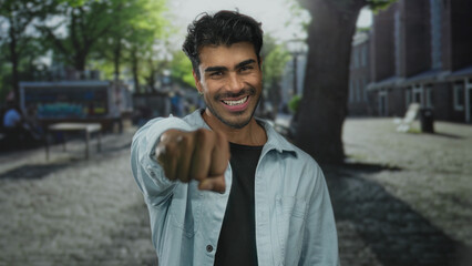Man wearing casual shirt thrusts fist forward toward camera in playful punch gesture on sunny...