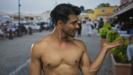 Shirtless smiling young hispanic man making ok sign with raised hand and bare chest on street;...