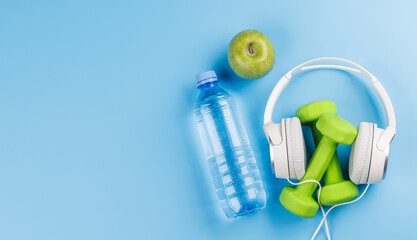 Flat lay of headphones and dumbbells over a bright blue background