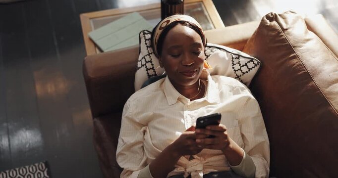 Typing, sofa and black woman with phone in home for social media, online message and funny website. Living room, above and person on smartphone laughing for internet, networking and connection