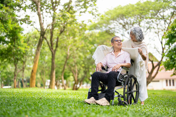 An adult man with a disability in wheelchair with a woman in a summer park .The woman and the man...