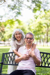 Elderly couple sitting on a bench in spring or summer park. Old man and woman outdoors, life in...