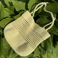 handmade yellow summer crochet bag on green leaves