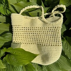 handmade yellow summer crochet bag on green leaves