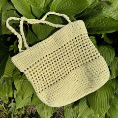handmade yellow summer crochet bag on green leaves