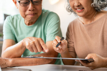 Happy senior couple using laptop counting taxes refund receipts to save money at home. Old man and...