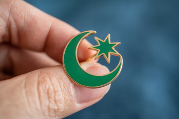 Elegant green crescent moon and star pin held by fingers, symbolizing faith, culture, and spiritual connection