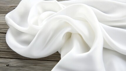 A white fabric with a smooth texture is draped over a wooden surface.