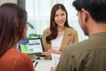 asian financial advisor presenting charts and data on a tablet during couple client meeting.financial planning and decision-making
