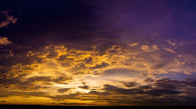 Dramatic sunrise with gradient orange and purple clouds, creating a panoramic abstract sky view. - Powered by Adobe