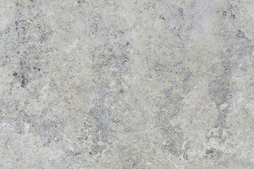 Fototapeta premium Detailed macro shot of a light gray and beige stone surface with dark speckles and subtle veining.