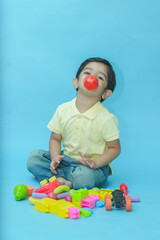 Indian child boy playing with educational toys isolated against blue background. 2-3 year playful kid having fun while sitting on the floor, Childhood.