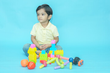 Indian child boy playing with educational toys isolated against blue background. 2-3 year playful...