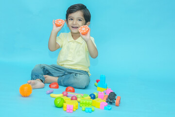 Happy Indian child boy playing with educational toys isolated against blue background. 2-3 year...