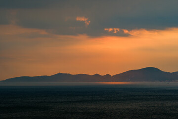 Obraz premium heavy raining in the sea with sunset sky over the island far away