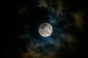 full moon in the midnight behind the cloudy sky