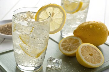 Refreshing lemonade with ice and fresh lemons on a light background