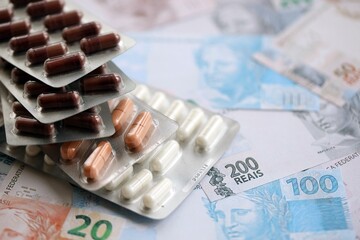 Brazilian reais banknotes and medicine pills. Brazil real money and drugs lies on table