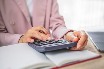 Close-up of businesswoman's hand using calculator to calculate family finance expenses.