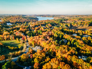 Aerial view of forested town in peak autumn with lakes in background