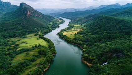 Fototapeta premium Aerial view of a winding river flowing through lush green valleys and mountains