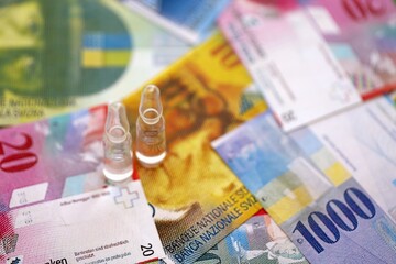 Swiss franc banknotes and medicine bottles. The current francs money bills and injection dose